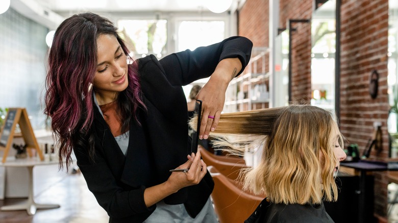 hairstylist cutting woman's hair