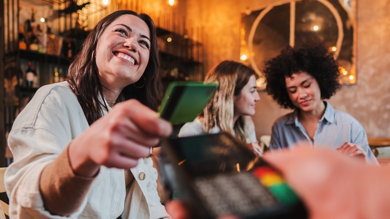 Woman smiles paying bill with friends