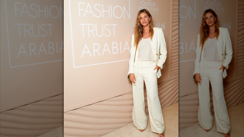 Gisele ﻿Bündchen poses in front of a sign for Fashion Trust Arabia