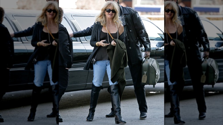 Goldie Hawn photographed near a car on a street wearing jeans, black boots, a black top, and sunglasses.