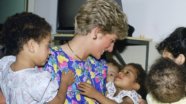 Princess Diana wearing a colorful floral dress hugging children in Brazil.