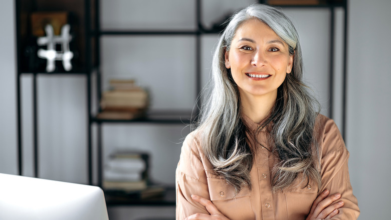 A woman smiles with curly gray hair