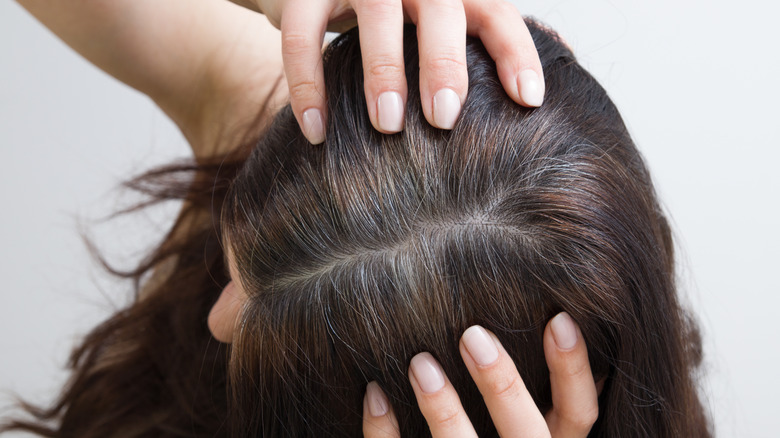 A woman pulls at her gray-brown hair