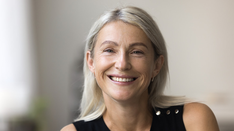 A woman smiling with creamy blond highlights in her gray hair.