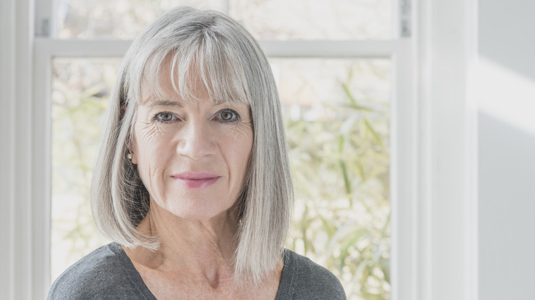 A woman smiles with a gray long bob