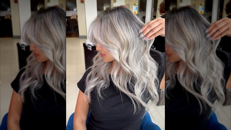A woman with platinum blond hair and gray roots