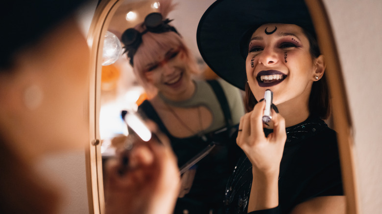 Woman doing Halloween makeup in mirror
