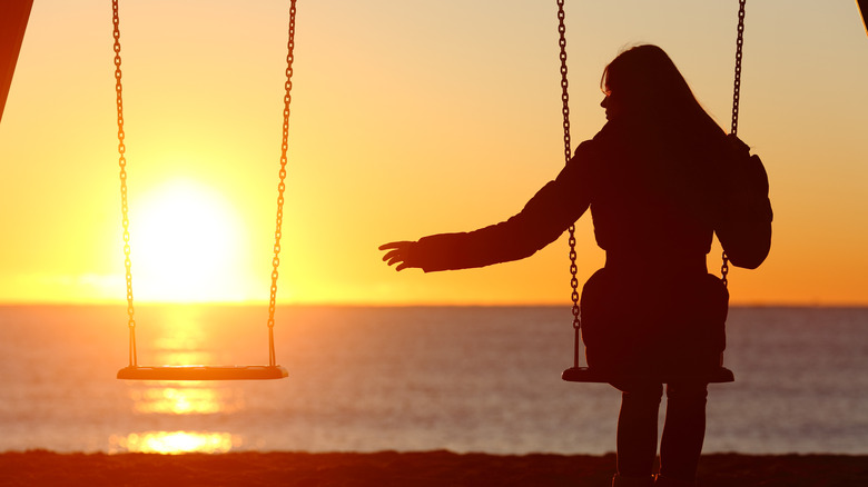 Woman on swing at sunset