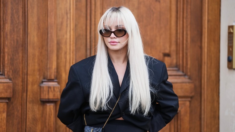 A woman with straight platinum blond hair and bangs.