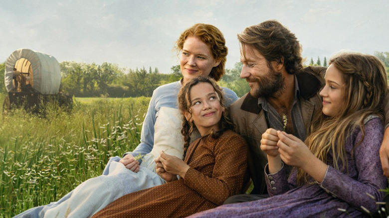 The Ingalls family in Netflix's "Little House on the Prairie" sitting in a grassy meadow.