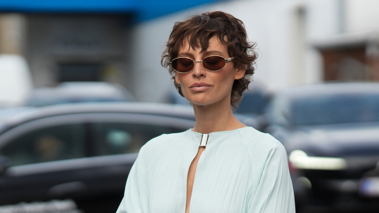 A person with a curly bixie wearing sunglasses