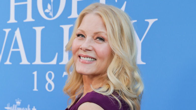 Barbara Niven smiling at a red carpet event with curly blond hair wearing a purple dress.