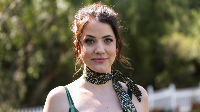 Julie Gonzalo with reddish brunette hair and a scarf tied around her heck