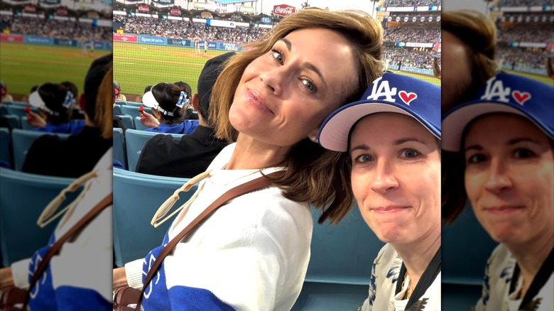 Nikki DeLoach posing for a selfie with friend Aimee Parker both wearing sports clothes attending a baseball game.