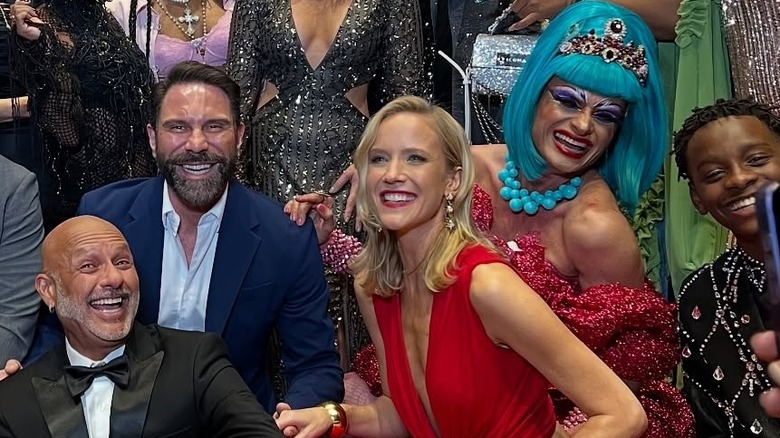 Jessy Schram poses with a group of people wearing red lips and a red cutout dress