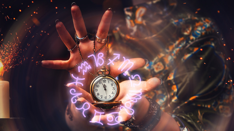 Person holding pocket watch surrounded by zodiac symbols