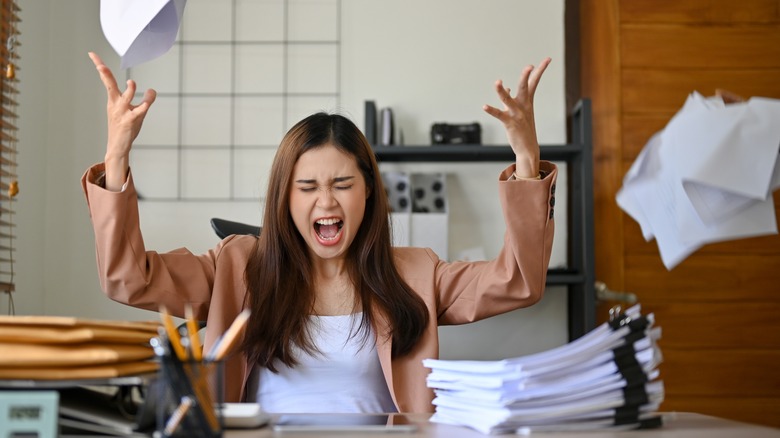 Woman throws papers from desk