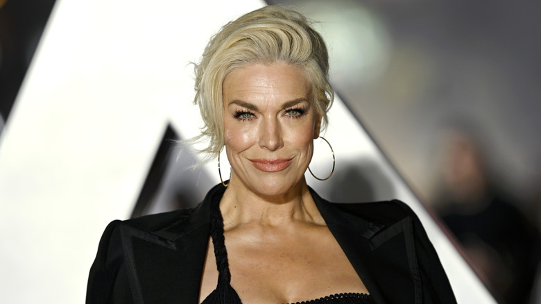 Hannah Waddingham with side swept bangs wearing a black top and gold hoop earrings.