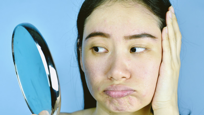 Asian woman looking at skin in the mirror