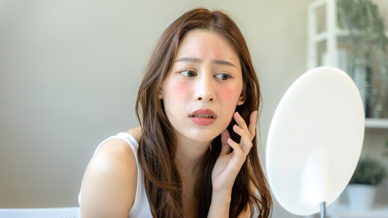 woman concerned looking into mirror