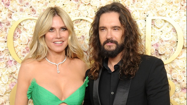 Heidi Klum wearing a green dress and posing with husband Tom Kaulitz at a red carpet event.