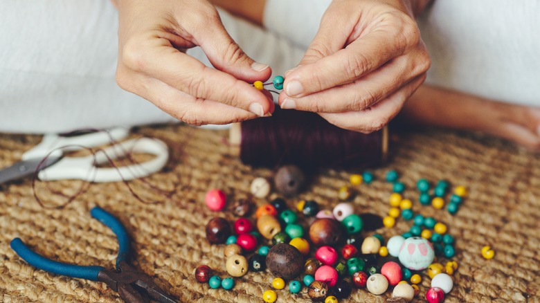 woman making beaded bracelet