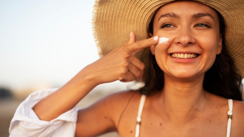 woman putting sunscreen on face