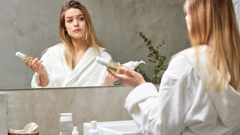 confused woman holds skincare products