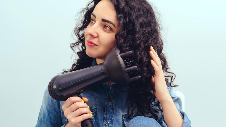 woman holding blow dryer with diffuser to dark, curly hair
