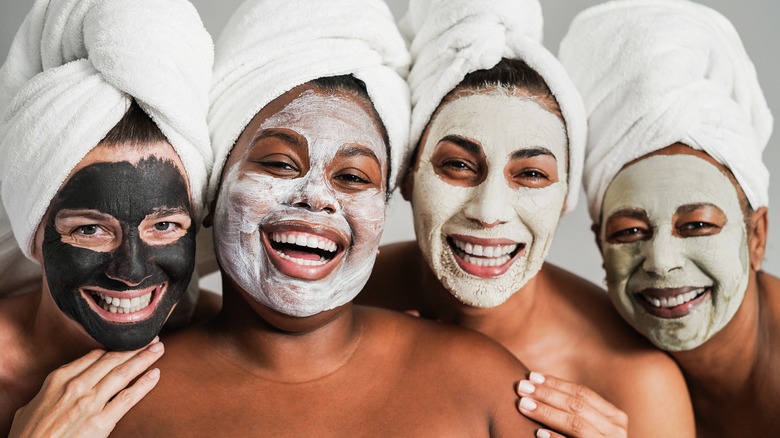 four smiling women in towels with four different types of face masks