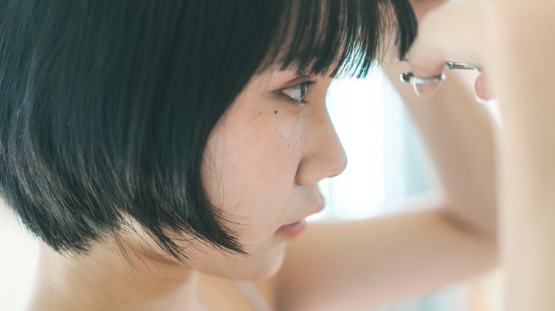 Asian woman cutting her bangs