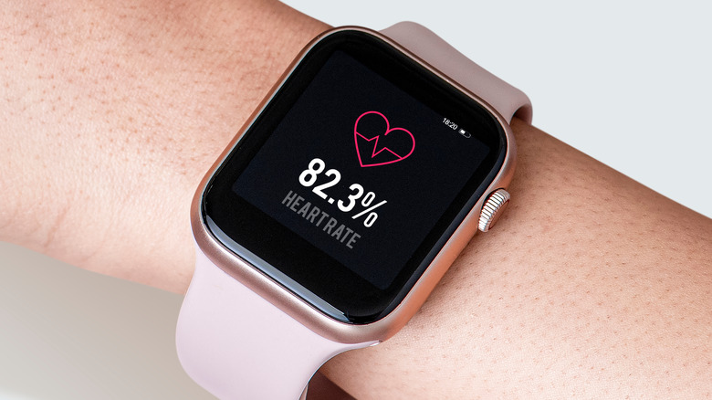 A smartwatch on someone's wrist displays heart rate