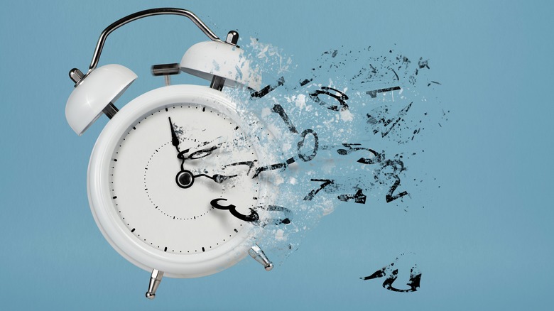 Disappearing alarm clock on plain background