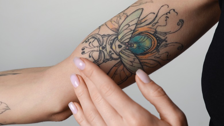 hand touching tattooed skin