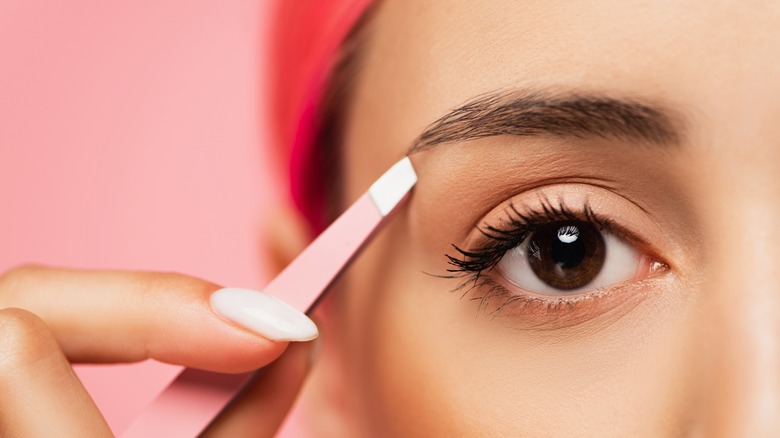 Woman tweezing her eyebrows