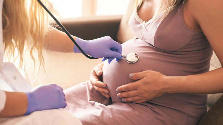 Pregnant belly with midwife's hands