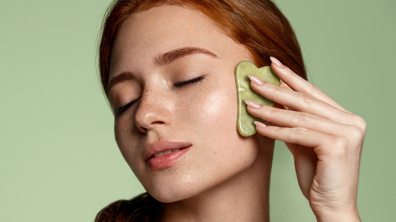 woman using a gua sha on her face