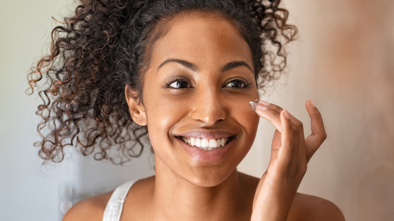 smiling woman applying face cream