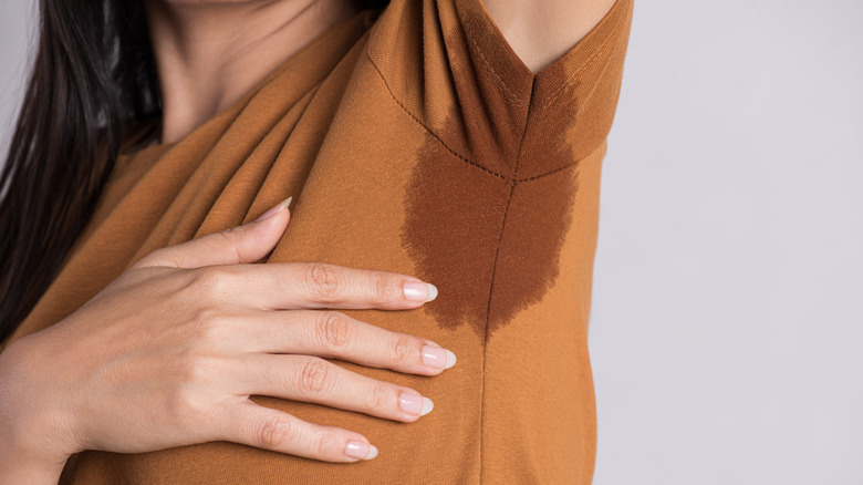 Woman with hyperhidrosis lifting arm to reveal sweat