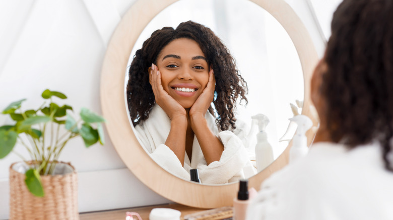 woman looking at skin in mirror