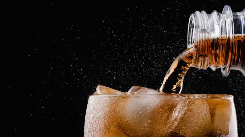 Soda being poured into glass with ice