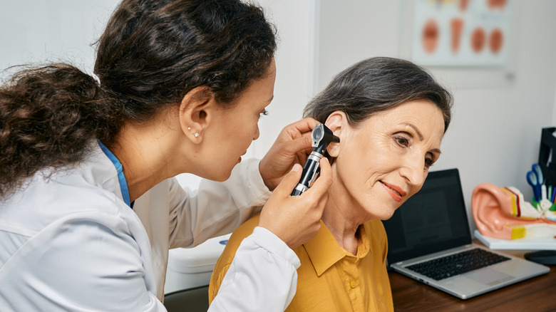 doctor examining patient ear in office 
