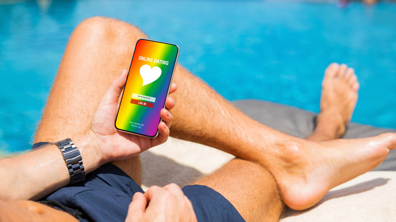 man using LGBTQ app by the pool