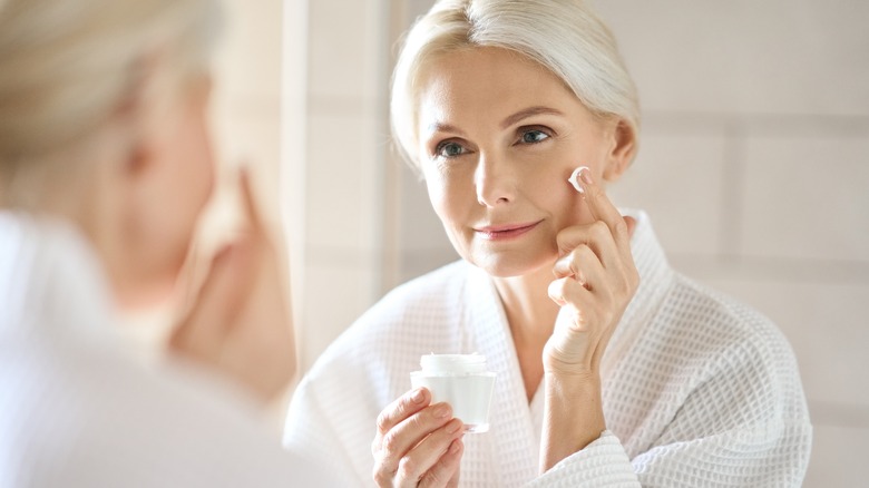 Older woman applying moisturizer on face