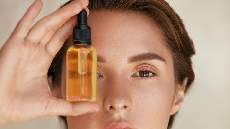 woman holding up bottle to eye