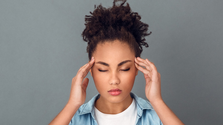 Model with ponytail massaging temples