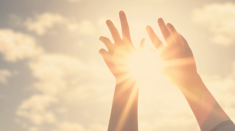hands reaching towards sun