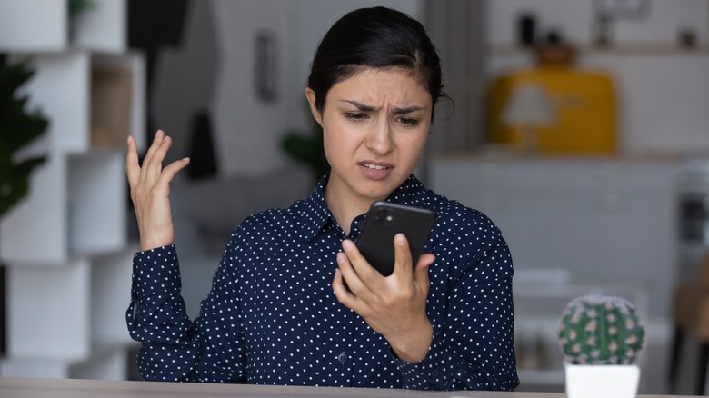 Confused woman looking at phone