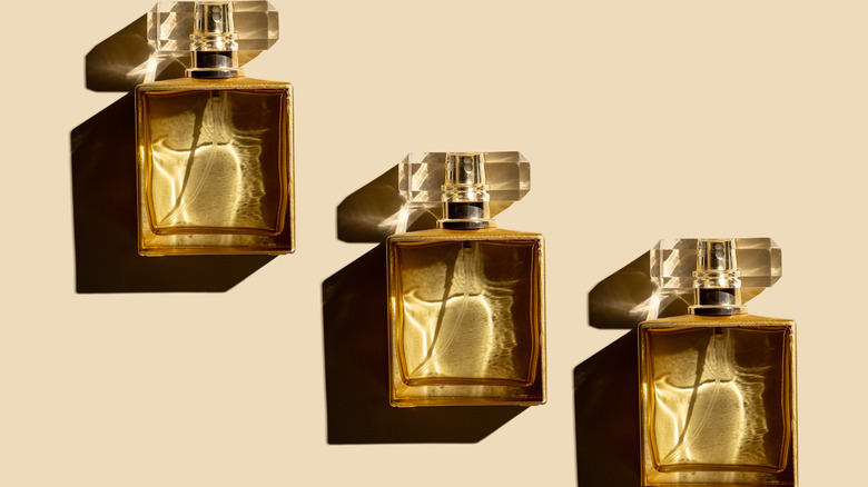 three bottles of perfumes against tan background