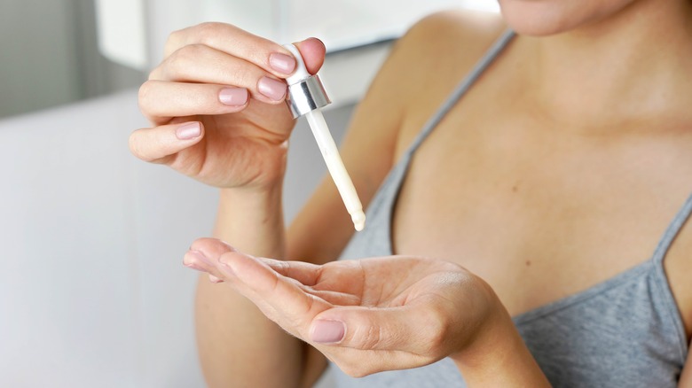 woman using dropper for skincare product